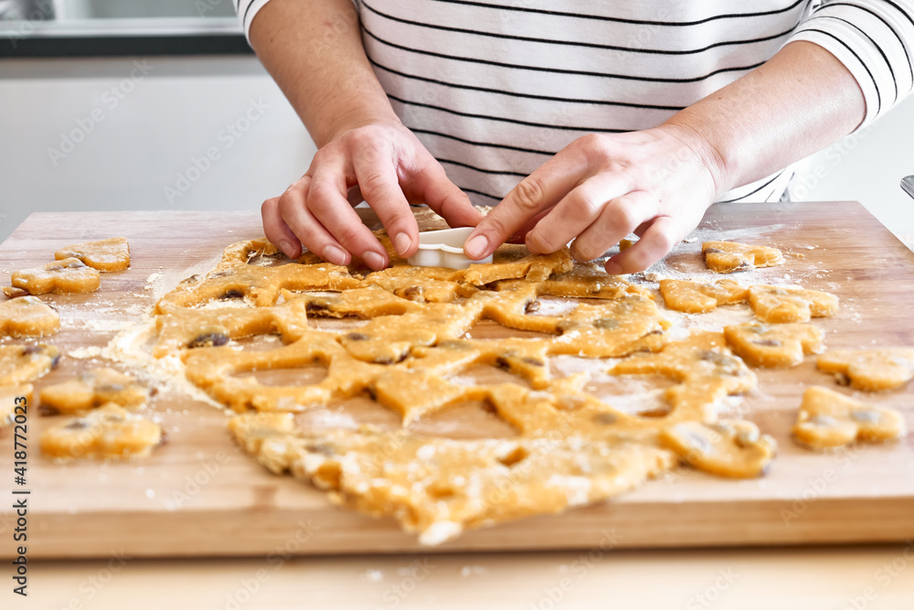 Woman making heart shaped cookies on the table in the kitchen. Gluten free flour cookies. Homemade healthy eating.