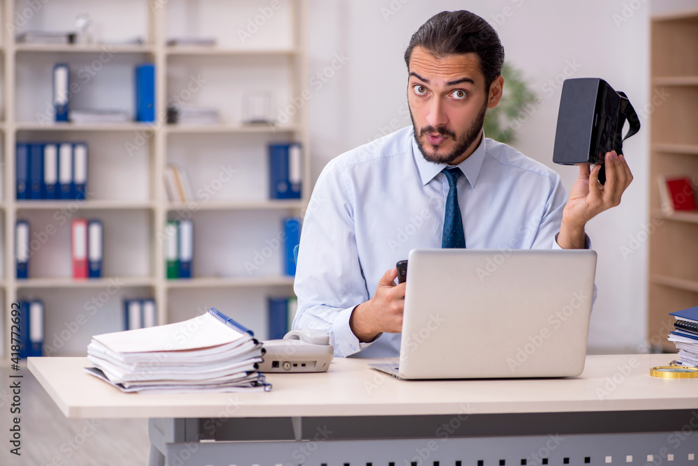 Young male employee wearing virtual glasses at workplace Young male employee wearing virtual glasses at workplace