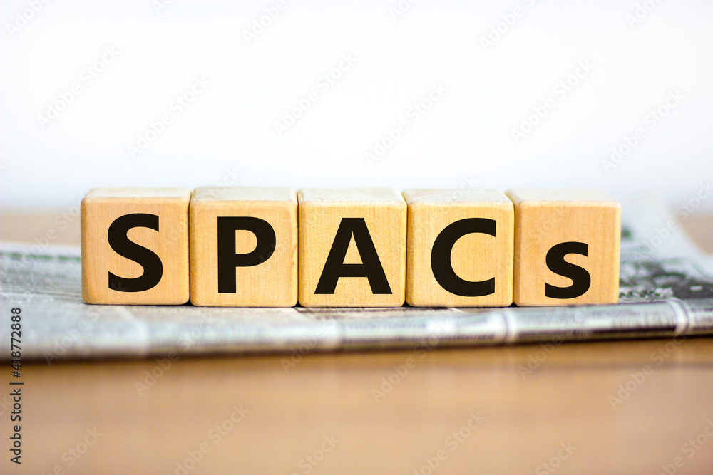 SPACs symbol. Wooden cubes with words 'SPACs, special purpose acquisition companies' on beautiful white background, copy space. Newspaper. Business and SPACs concept. SPACs symbol. Wooden cubes with words 'SPACs, special purpose acquisition companies' on beautiful white background, copy space. Newspaper. Business and SPACs concept.