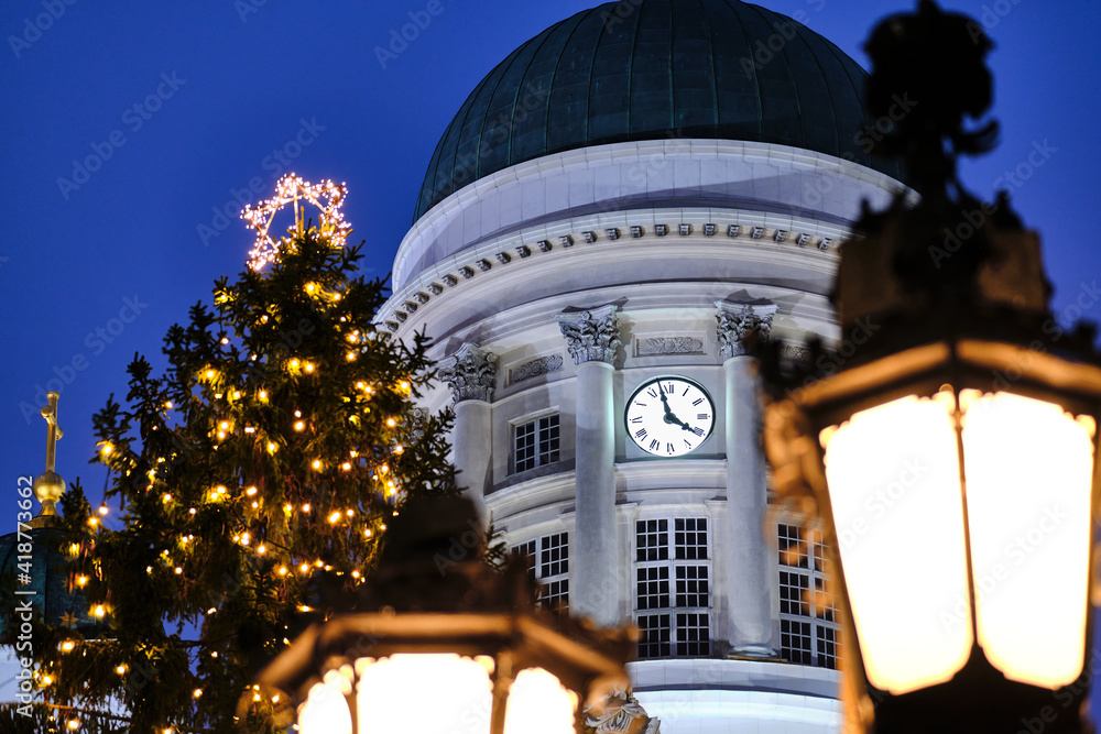 Old Clock on the Dome of Helsinki Cathedral, Finland. In the foreground the Christmas tree and the street lamp.