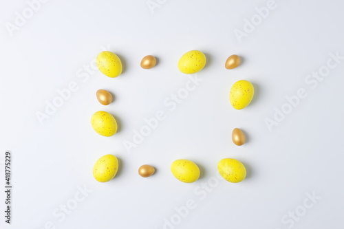 Easter yellow and golden eggs on white background. Flat lay, copy space.
