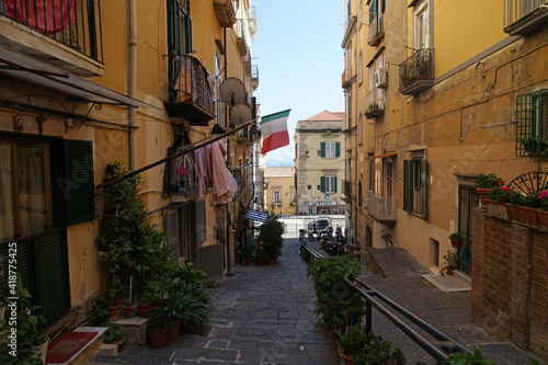 Naples steep narrow street with balconies with fresh linen and Italian flag, traditional living in Naples, Italy