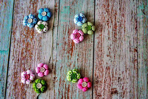 Easter decoration made of colorful fabric flowers with a button in the middle, lying on a wooden surface.