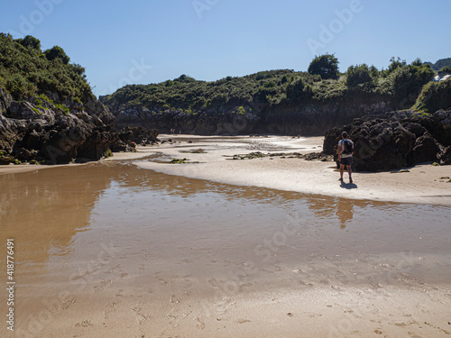 Vista de turista caminando por la arena de la playa de Entremares y Buelna en Asturias, España, verano 2020.
