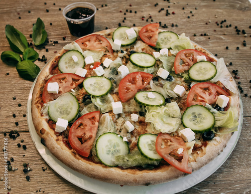 Vegetable pizza with mozzarella, fresh tomatoes and cucumber. Green basil leaves