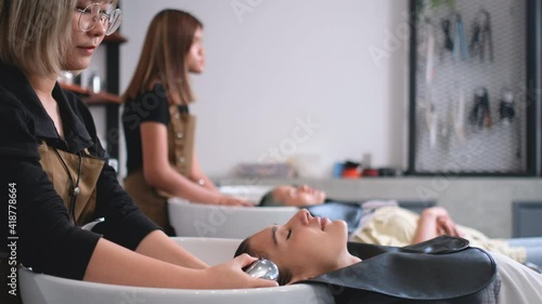 Wide shot beauty salon barber woman wash hair of beautiful woman and she look relax and happy. Beauty business for healthy and good appearance of people concept.