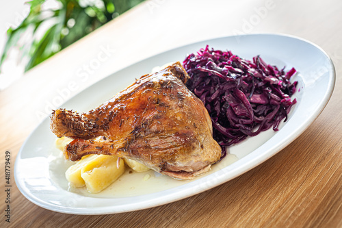 Cooked food - roasted duck leg, red cabbage, potato dumplings.