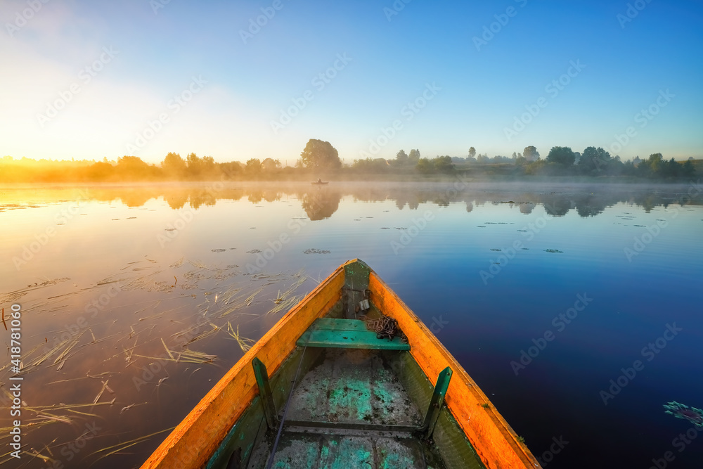 Fishing boat at beautiful foggy sunrise on a lake