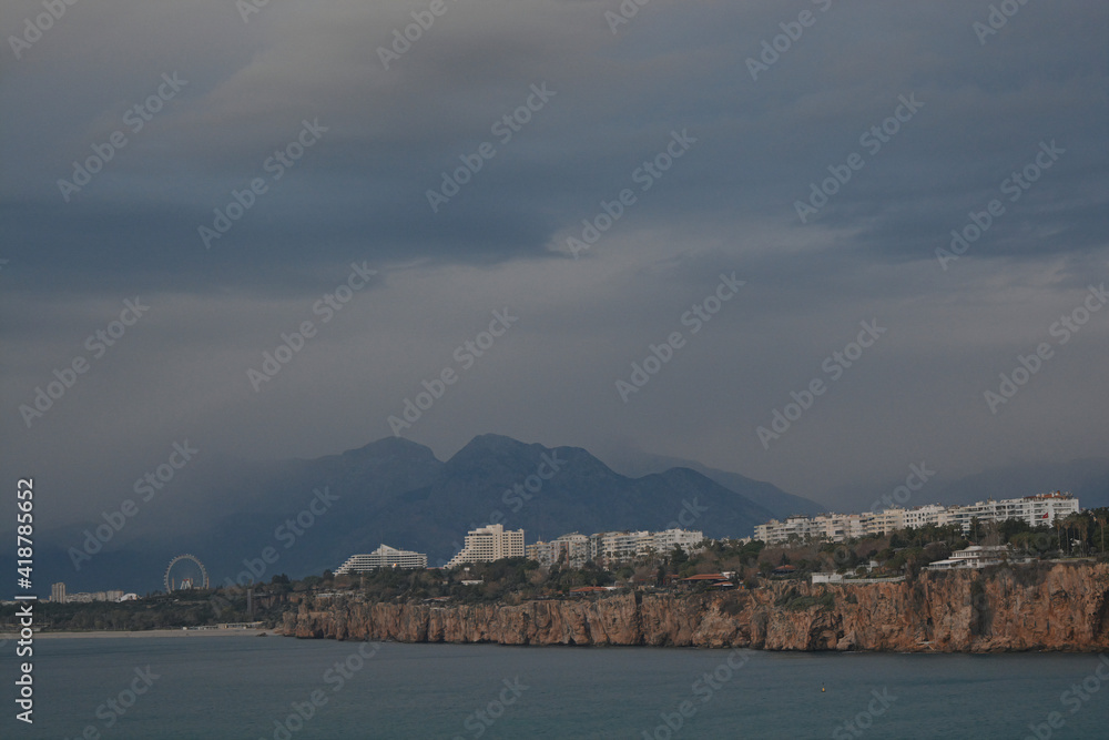 sea, grey clouds and mountains with foggy weather, settlements