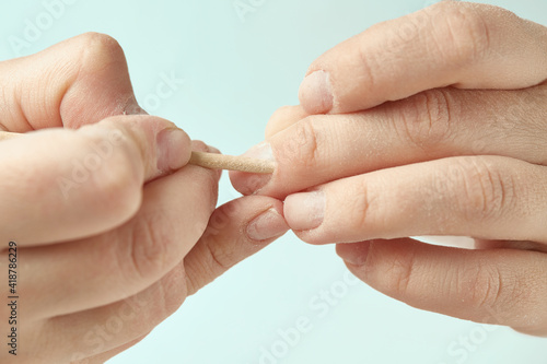 Cuticle treatment with an orange stick during a nail edging manicure. The girl makes a manicure at home. Cuticle treatment with an orange stick on an isolated background. Close-up.