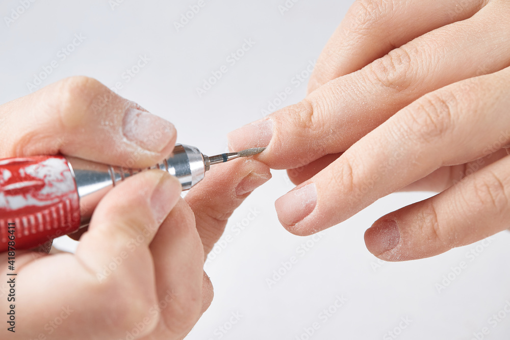 The cutter is a needle for processing the cuticle during the hardware manicure of the nails. The girl makes herself a hardware manicure at home. Cuticle treatment on a white isolated background. The cutter is a needle for processing the cuticle during the hardware manicure of the nails. The girl makes herself a hardware manicure at home. Cuticle treatment on a white isolated background.