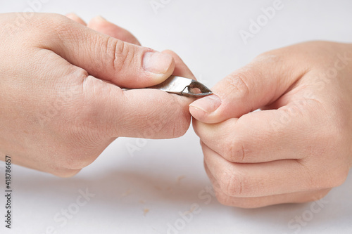 Treatment of the cuticle with forceps during the edged nail manicure. The girl makes herself an edged manicure at home. Cuticle treatment with forceps on a white isolated background. Close-up.