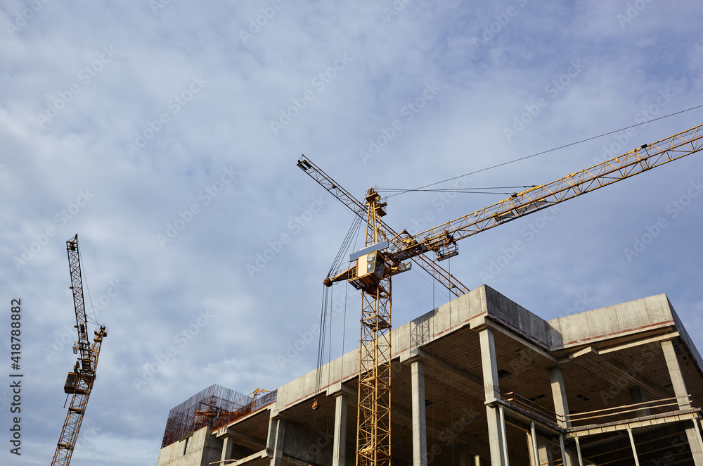 Tower cranes building a house. Concrete building under construction Tower cranes building a house. Concrete building under construction