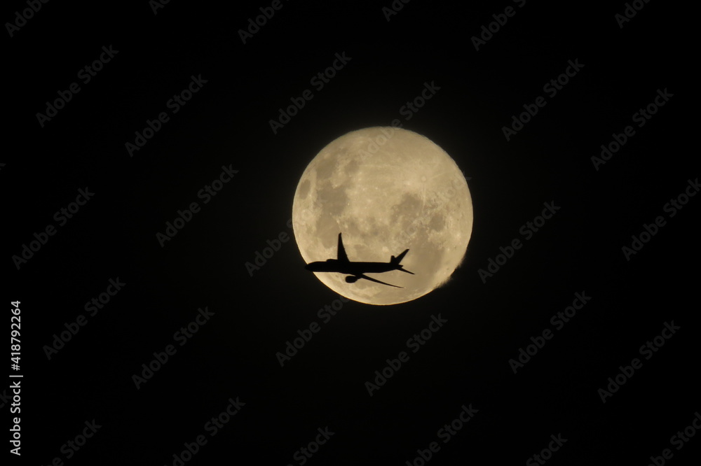 avião de passagem na frente da lua