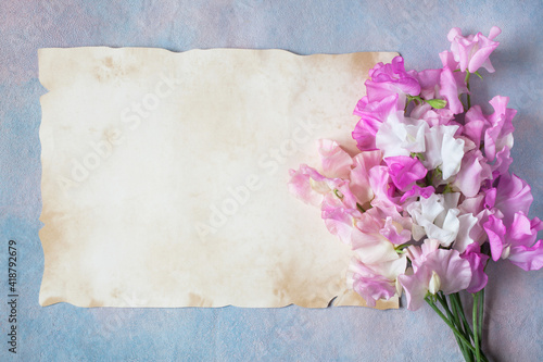 Bouquet of sweet pea flowers and paper with space for text greeting on decorative background.