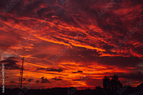 Amazing red sunset or dawn sky, view under roofs and trees. Violet and orange colors.