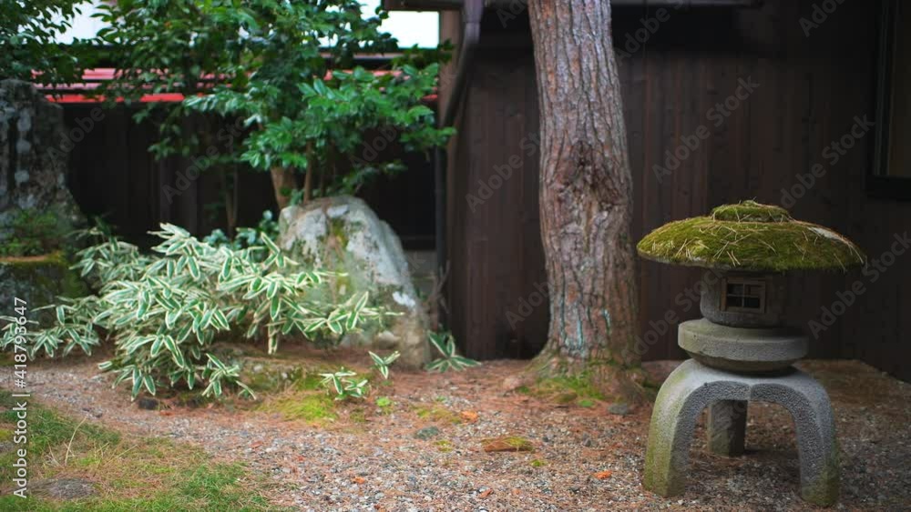 Traditional small inside indoor Japanese garden in Japan with gravel rocks and stone lantern lamp at home or house in rainy raining weather Traditional small inside indoor Japanese garden in Japan with gravel rocks and stone lantern lamp at home or house in rainy raining weather