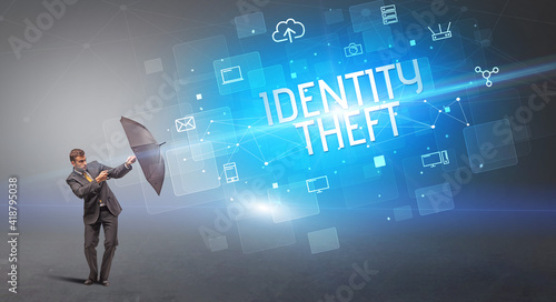 Businessman defending with umbrella from cyber attack and IDENTITY THEFT inscription  online security concept
