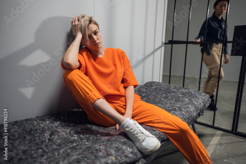 Sad criminal girl in her cell on a bed worries about her fate.