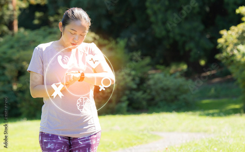 Running woman with smart watch. Concept of The technology to check health while exercising, Exercise for health or warm-up body, fresh air, or Oxygen in the green tree in the park in sunlight.