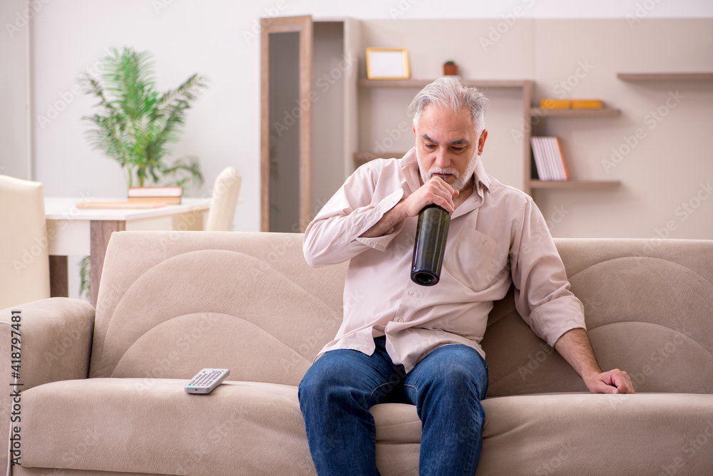 Obraz premium Old man drinking alcohol at home