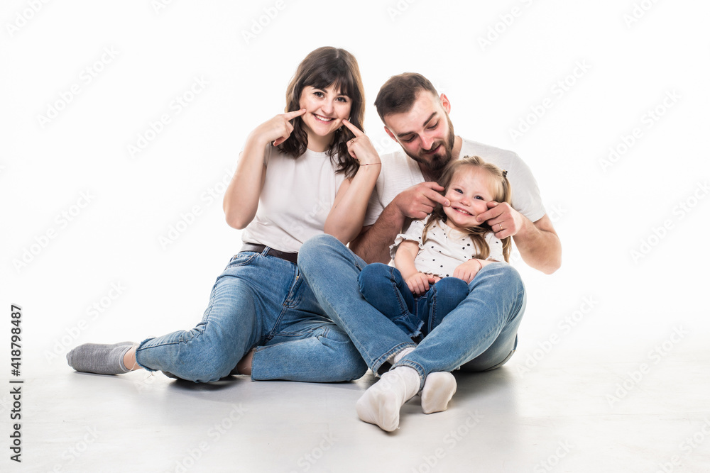 Relationship concept. Beautiful young family smiling pointed teeth and have a fun time together while sitting on the floor and looking on camera. Relationship concept. Beautiful young family smiling pointed teeth and have a fun time together while sitting on the floor and looking on camera.