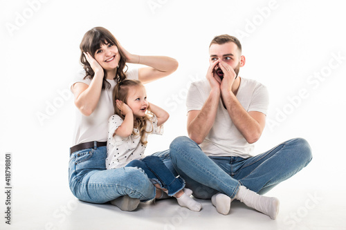 Young mother with daughter cover ears when scream father while sitting on the floor isolated on white background