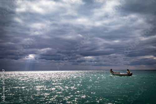 Two fishermen in a boat in the Black Sea under dramatic cluds and light, Bulgaria