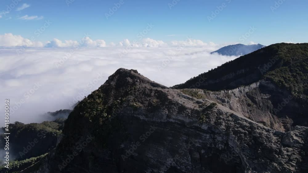 Aerial shot over the edge of irazu volcano crater sunny day over clouds Costa Rica Cartago Aerial shot over the edge of irazu volcano crater sunny day over clouds Costa Rica Cartago