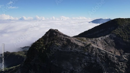Aerial shot over the edge of irazu volcano crater sunny day over clouds Costa Rica Cartago photo