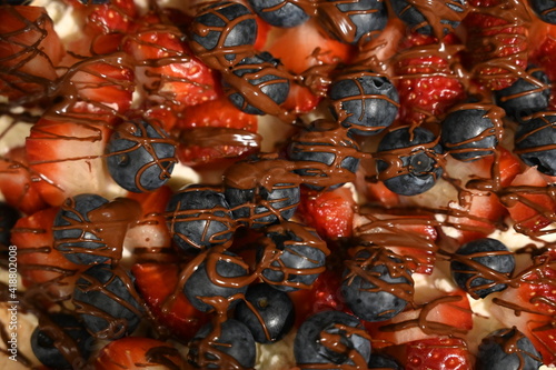 Top view of fruit cake. Sweet pavlova cake with fresh strawberries, blueberries and chocolate.