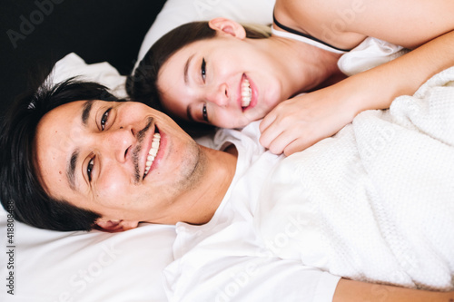 young couple in bed smiling at the bed