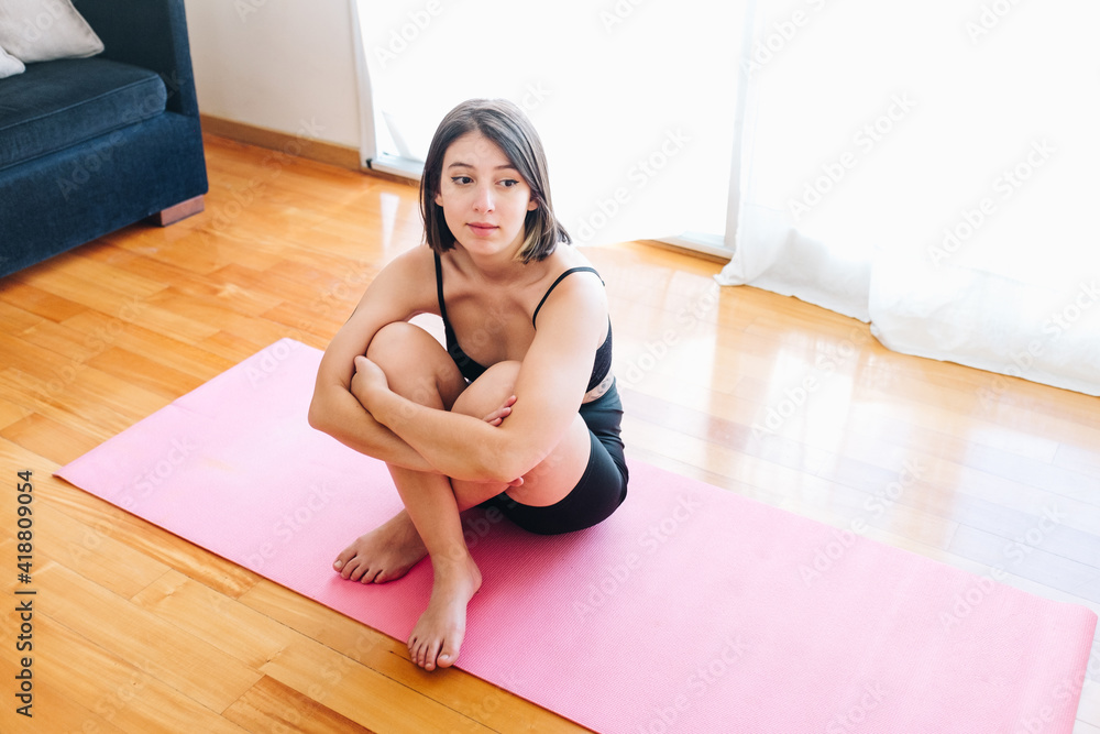 Thoughtful girl hugging her legs sitting on a play mat