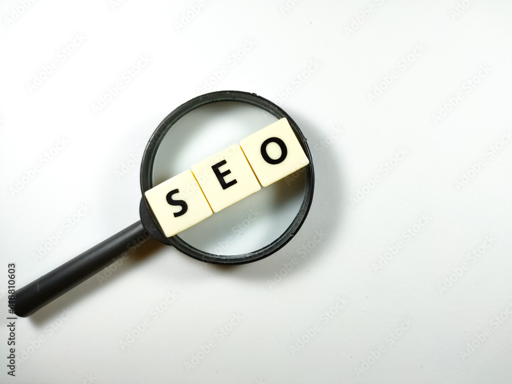 Selective focus.Magnifying glass and scrabble letters with text SEO (search engine optimization) on white background. Selective focus.Magnifying glass and scrabble letters with text SEO (search engine optimization) on white background.