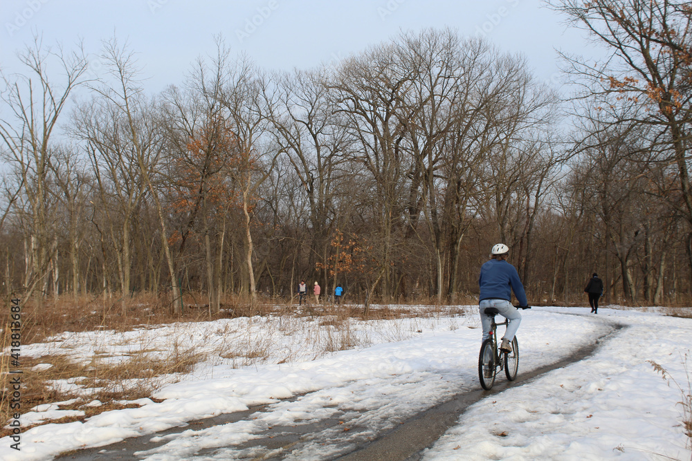 Bicycle rider and four walkers on the North Branch Trail at Miami Woods in Morton Grove, Illinois in winter