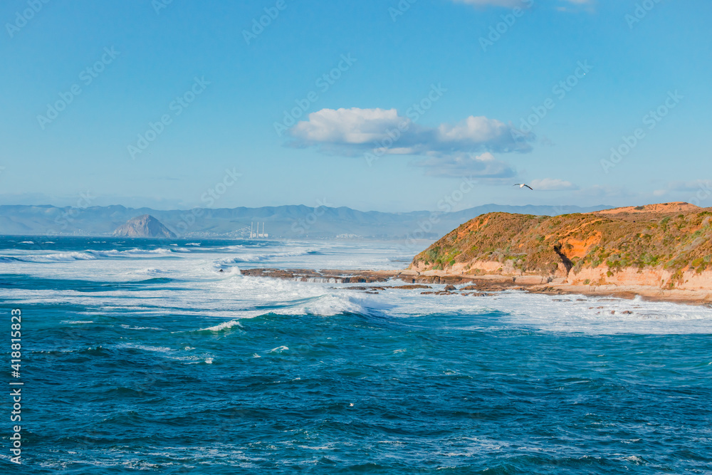 Seascape in blue and turquoise colors. Pacific ocean, cliffs, and silhouette of Morro Rock. View from Montana del Oro state park, California coastline Seascape in blue and turquoise colors. Pacific ocean, cliffs, and silhouette of Morro Rock. View from Montana del Oro state park, California coastline
