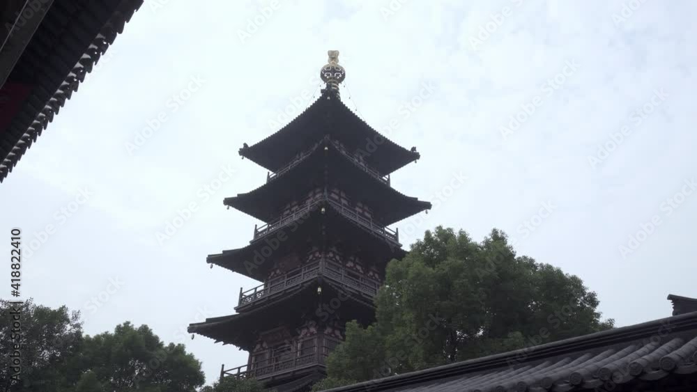 Low angle view of tall traditional Buddhist temple by trees against sky - Suzhou, China Low angle view of tall traditional Buddhist temple by trees against sky - Suzhou, China