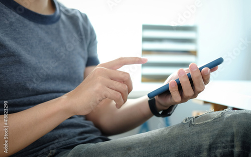 Man hold with smart phone at sit on sofa and use phone happily at home. 