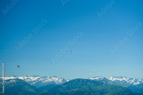 ein Gleitschirm Segler fliegt über den Alpen vor blauem Himmel und Bergpanorama