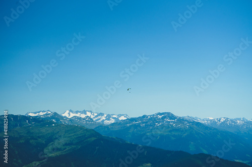ein Paraglider allein vor dem weiten Himmel über den Bergspitzen des Tirol und der Tauern in Österreich