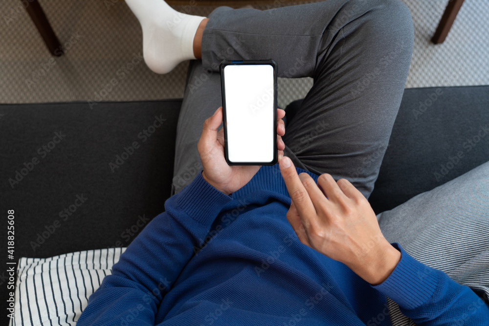 Handsome Asian teenager man wearing casual clothes in glasses using smart phone browsing Internet on mobile phone device at the living room. Handsome Asian teenager man wearing casual clothes in glasses using smart phone browsing Internet on mobile phone device at the living room.