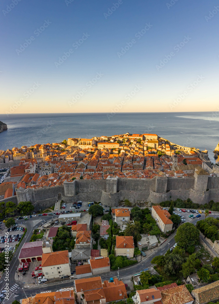 Aerial drone shot of City Walll Dubrovnik half in sunrise sun light in Croatia summer