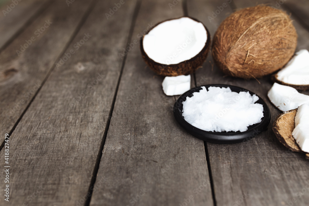 Broken coconuts on gray wooden background. White fresh pulp on black plate Broken coconuts on gray wooden background. White fresh pulp on black plate