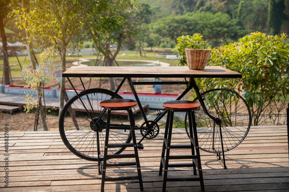 Two chairs and a bicycle table with wood basket on it  outdoor at coffee shop.