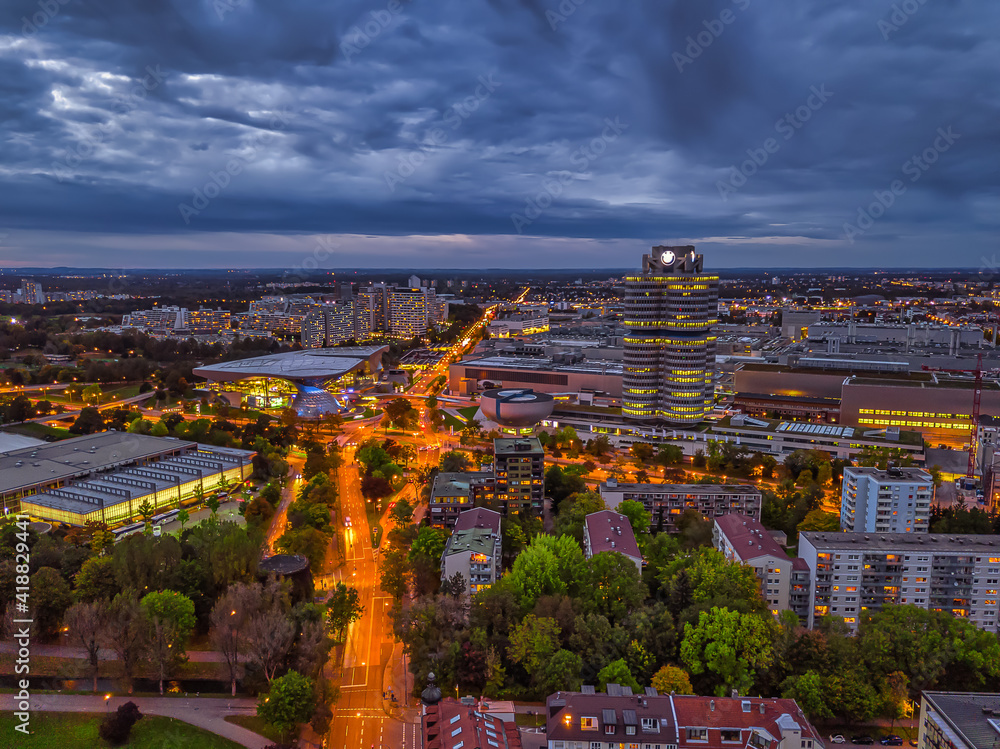 Wonderful twilight view over the illuminated Munich with business district and cars on a road from a high perspective.