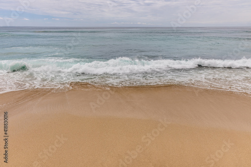 Seascape background. Sandy beach, milky foam waves, blue ocean. Scenic waterscape. Horizon line. Nature and environment concept. Daylight. Copy space. Dreamland beach, Bali