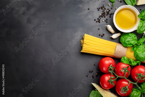 Spaghetti with ingredients for making pasta on a dark background, top view. Flat lay