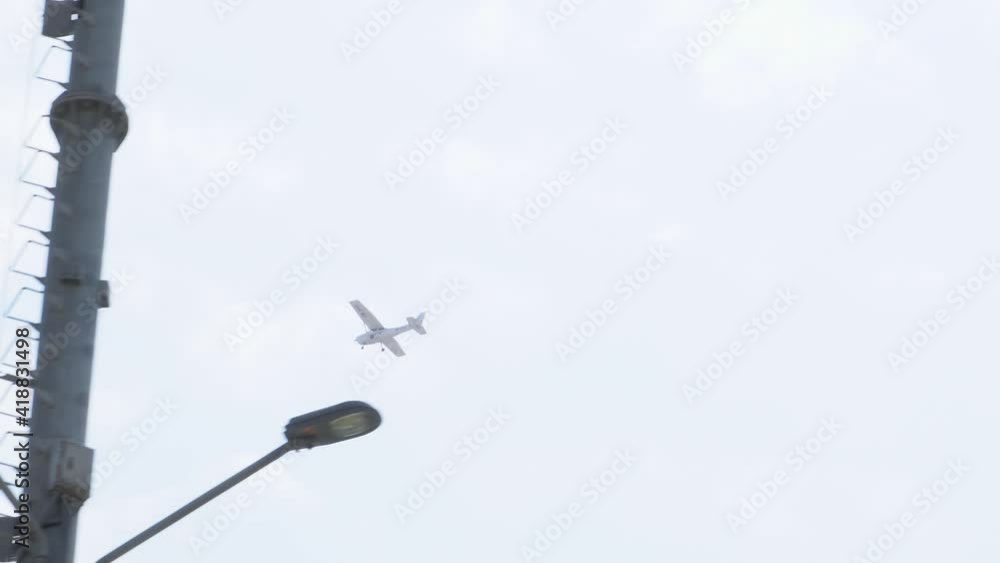 a plane flying through the skies seen from the ground between trees and lighthouses a plane flying through the skies seen from the ground between trees and lighthouses