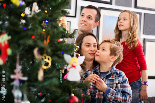 Happy family decorating Christmas tree at home © JackF