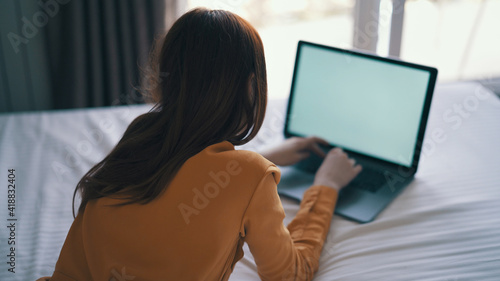 woman lying on bed working in front of laptop at home internet